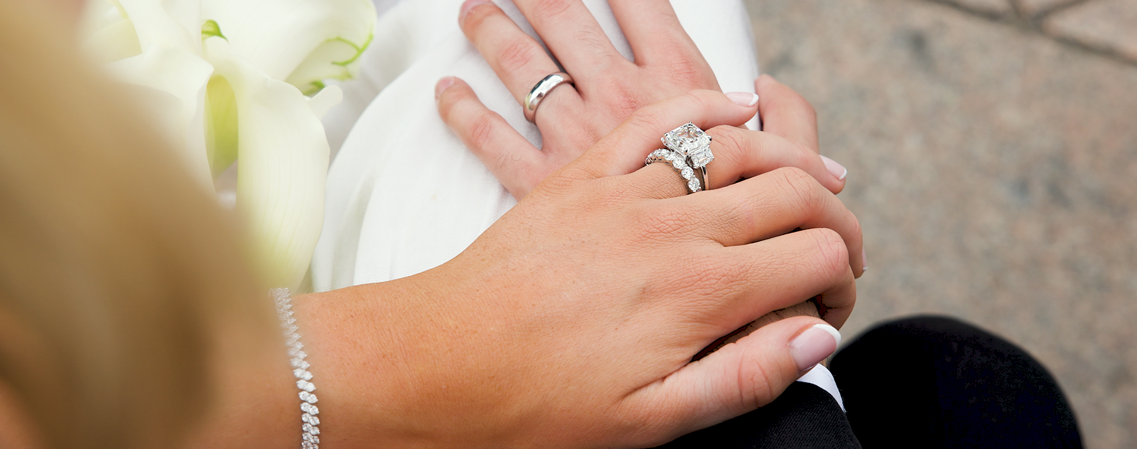Close-up of hands holding a bouquet with wedding rings on a blurred background